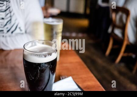 Foyer peu profond d'une pinte presque pleine d'une bière irlandaise populaire vue sur une table en bois. Banque D'Images