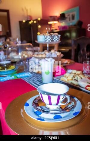 Thé coloré avec table, tasses à thé et soucoupes de fantaisie, avec des aliments sucrés et salés sur des plateaux Banque D'Images