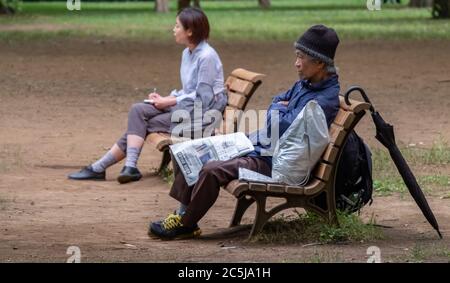 Un vieil homme sans abri et une jeune femme assis sur un banc en bois séparé. Banque D'Images