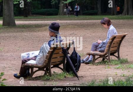 Un vieil homme sans abri et une jeune femme assis sur un banc en bois séparé. Banque D'Images