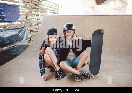 Groupe d'amis athlètes skateboarders se posant ensemble dans un parc de skate. Les enfants du Caucase s'amusent ensemble sur les sports urbains zone extérieure pour Banque D'Images