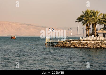 Israël, Tibère, Mer de Galilée, Bateaux sur la Mer de Galilée et quai d'un hôtel de bord de mer à Tibère. De l'autre côté du lac se trouvent les hauteurs du Golan, occupées par Israël. Banque D'Images