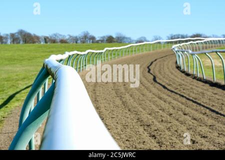 Un petit foyer de clôtures tubulaires légères vues sur une piste de course professionnelle. La piste souple a été mise en rack depuis la dernière course. Banque D'Images