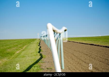 Un petit foyer de clôtures tubulaires légères vues sur une piste de course professionnelle. La piste souple a été mise en rack depuis la dernière course. Banque D'Images