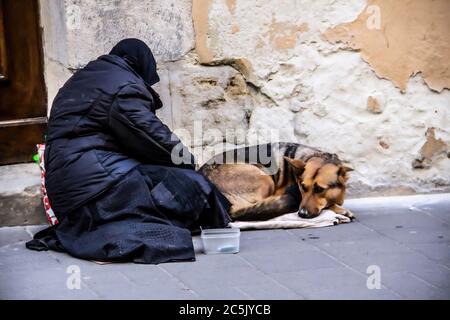 Une femme mendiante demande des almes avec son chien. Banque D'Images