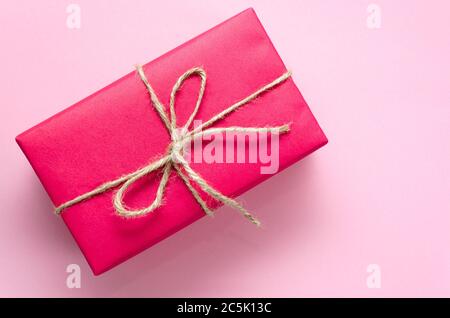 Boîte-cadeau rose attachée avec une ficelle sur fond rose clair. Concept de vacances. Idée de cadeau DIY. Flat lay, vue de dessus. Copier l'espace Banque D'Images