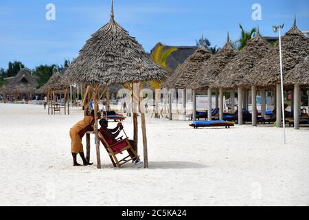 Kendwa, Zanzibar - 4 octobre 2019 : homme de la tribu Masai en robe traditionnelle et homme de personnel montré sur la plage de Kendwa le soir. Tanzanie, Afrique Banque D'Images