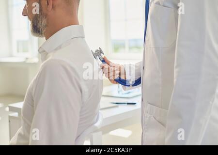 Femme dotcore écouter un patient utilise un stéthoscope dans une clinique. Soins médicaux pour les malades par un professionnel de la santé. Banque D'Images