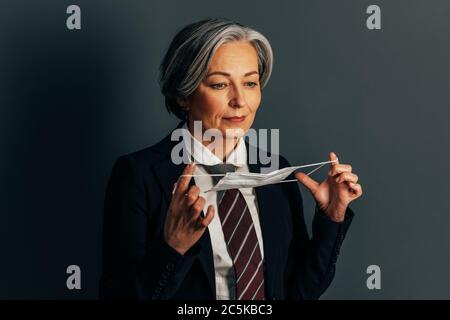 Femme d'affaires mature qui va mettre sur le masque de protection. Faire des affaires après une pandémie. Concept de quarantaine. Image teintée Banque D'Images