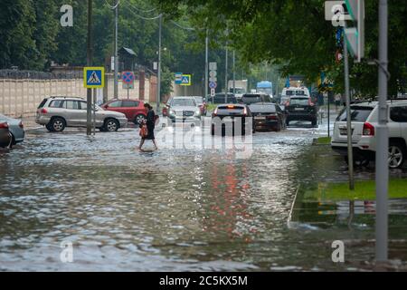 Moscou 18/06/2020 une femme traversant la rue inondée d'eau après de fortes pluies, voitures roulant par les inondations Banque D'Images