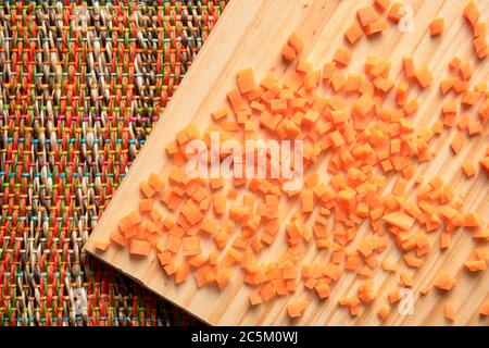 Dés de carottes crus sur une planche à découper en bois. Vue de dessus. Banque D'Images