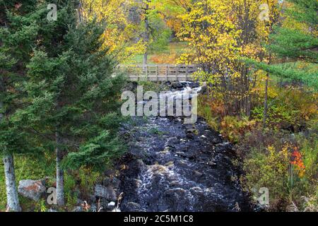 Pont sur l'eau. Petite passerelle en bois au-dessus d'un ruisseau et d'une chute d'eau au parc de bord de route de Tioga Falls près de Marquette Michigan Banque D'Images