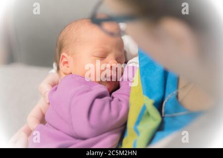 Maman tient sa petite fille d'un mois sur l'épaule pendant qu'elle dort. Banque D'Images