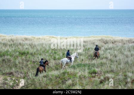 Trois cavaliers sur les dunes herbeuses de la côte de Wexford en Irlande Banque D'Images