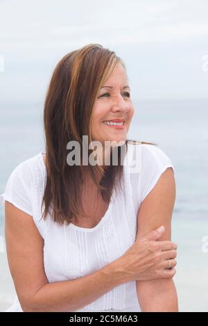 Portrait belle femme brune mûre heureuse et détendue souriante en plein air, avec un arrière-plan flou. Banque D'Images