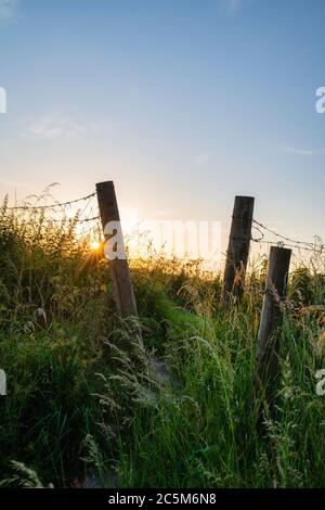 Coucher de soleil à travers une barrière de chemin de pied s'enferme en face de silbury colline au coucher du soleil. Avebury, Wiltshire, Angleterre Banque D'Images