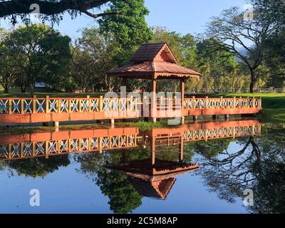 Passerelle au-dessus d'un lac, ciel bleu, arbres et réflexions dans l'eau Banque D'Images