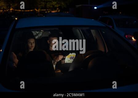 Ptuj, Slovénie. 03ème juillet 2020. Un jeune couple à l'arrière de sa voiture mange de la nourriture rapide tout en regardant un film "Grease" avec John Travolta et Olivia Newton-John dans un parking de cinéma temporaire en voiture.en raison de la propagation du coronavirus (COVID-19), le City Cinema a organisé une projection en plein air. Crédit : SOPA Images Limited/Alamy Live News Banque D'Images