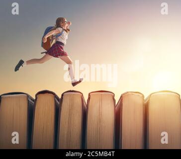 Retour à l'école! Joyeux mignon enfant industriel sont en train de courir sur des livres sur fond de paysage de coucher de soleil. Concept d'éducation et de lecture. Le développement Banque D'Images