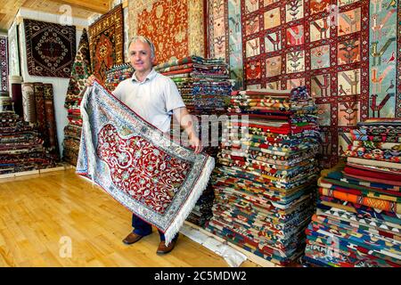 Un vendeur turc de tapis expose un tapis dans une boutique de la vieille ville de Kaleici à Antalya en Turquie. Banque D'Images