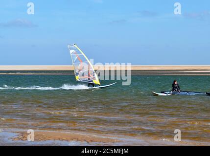 Surfeur sur l'estuaire traversant Wells Next the Sea Beach, Norfolk, Royaume-Uni Banque D'Images