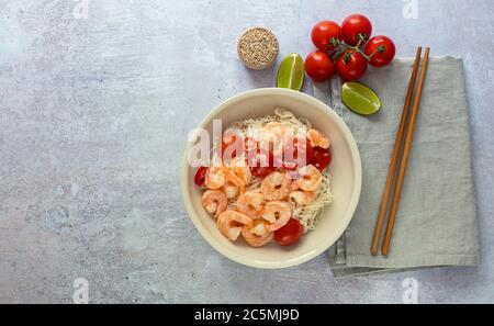 Nouilles alimentaires keto shirataki konjak avec crevettes et tomates dans un bol avec baguettes. Banque D'Images