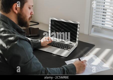 Homme d'affaires remplissant des documents et travaillant avec un ordinateur portable. Concept de finance et comptabilité. Homme écrivant et utilisant l'ordinateur. Banque D'Images