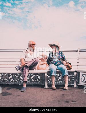 Un couple âgé se détendant sur un banc au bord de la mer parler Banque D'Images