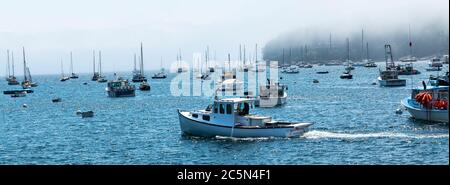 Rockport, Maine, Etats-Unis - 4 août 2017 : un bateau de pêche se déplaçant à travers de nombreux voiliers amarrés et des canots de loster dans un matin brumeux à Bar Harbor Maine. Banque D'Images