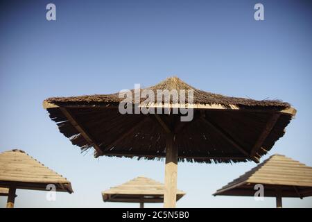 des canopies de paille sur la plage contre le ciel bleu. Banque D'Images