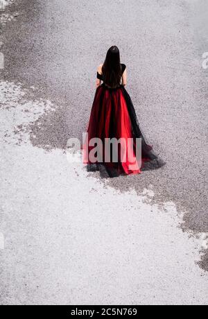 Femme dans une robe marchant sur une route partiellement humide Banque D'Images