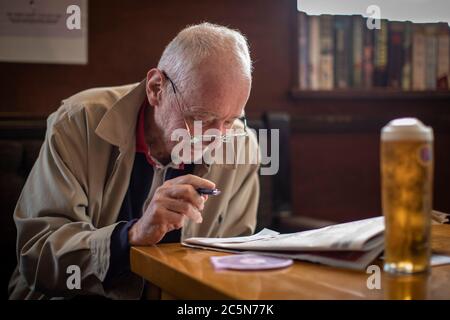 Norwood Ouest, Angleterre. 4 juillet 2020. Un homme âgé qui fait la croix dans le journal tout en appréciant une pinte de plus grande taille à son pub local, la Horns Tavern à West Norwood, suite à l'annonce du gouvernement britannique pour assouplir les règles de verrouillage. Les pubs, bars et restaurants rouvrent aujourd'hui, ayant été fermés pendant plus de trois mois au Royaume-Uni en raison de la pandémie du coronavirus. (Photo de Sam Mellish / Alamy Live News) Banque D'Images