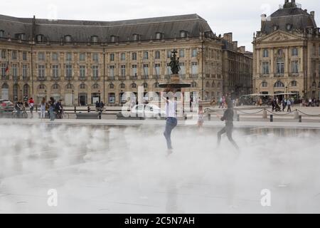 Bordeaux, Aquitaine / France - 06 10 2018 : fille dansant et éclaboussant le miroir d'eau sur la place de la bourse à Bordeaux, France Banque D'Images