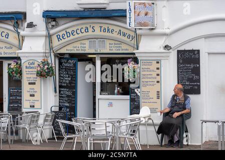 Southend on Sea, Essex, Royaume-Uni. 4 juillet 2020. Les pubs, restaurants et autres entreprises en Angleterre sont libres d'ouvrir leurs portes aux clients pour la première fois depuis le verrouillage du coronavirus COVID-19. Le gouvernement leur permet d'ouvrir à partir de 6h du matin comme facilité de verrouillage des mesures. À Southend on Sea, les arcades d'amusement en bord de mer et le parc à thème Adventure Island ont ouvert, bien que le temps froid venteux garde beaucoup de gens à l'écart. Aucun client pour ce café, avec un travailleur de sexe masculin assis en attendant pour affaires Banque D'Images