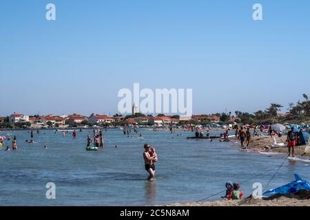 Les gens apprécient la mer peu profonde à Queen's Beach avec la petite ville historique de Nin en arrière-plan, le comté de Zadar, Dalmatie, Croatie Banque D'Images