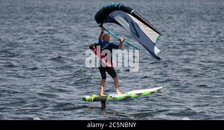 Berlin, Allemagne. 04e juillet 2020. Un surfeur à ailes fait le tour des vagues du Tegeler See. Le surf sur les ailes offre une combinaison de planche à voile et de kite. Crédit : Paul Zinken/dpa/Alay Live News Banque D'Images