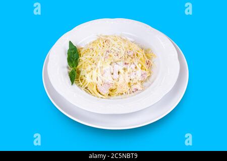 Délicieux spaghetti italiens Carbonara au fromage, au bacon et à la menthe fraîche isolés sur fond bleu Banque D'Images