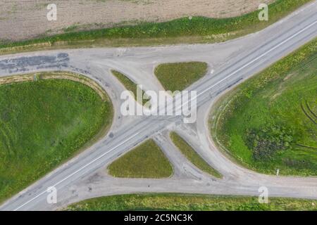 Vue aérienne en haut de l'échangeur ou de l'intersection sans circulation sur la route. Champ vert Banque D'Images