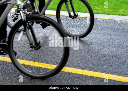 roues de deux bicyclettes roulant le long d'une route asphaltée avec marquage jaune, arrière-plan sur le thème du cyclisme. gros plan. Banque D'Images