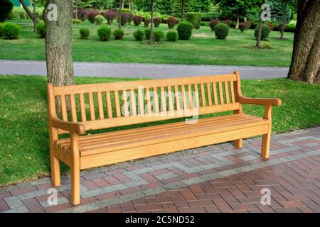 banc en bois dans le parc bien entretenu avec des plantes vertes un jour d'été, personne. Banque D'Images