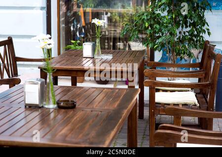 café extérieur avec tables gratuites pour se détendre en plein air près de la façade du bâtiment avec une fenêtre et pots de fleurs avec plantes. Banque D'Images