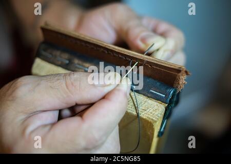 Les mains des hommes sont cousues grand en cuir avec une couture manuelle. Banque D'Images