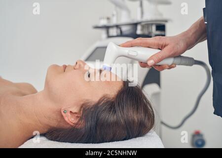 Femme aux cheveux foncés subissant une procédure de serrage de la peau Banque D'Images