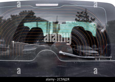 verre sale dans une couche de poussière essuyée par un essuie-glace, près de la lunette arrière de la voiture noire chauffée. Banque D'Images