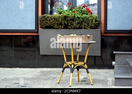 Table en osier avec une boîte de façade traditionnelle italienne unaire d'un restaurant de couleur sombre avec un pot de fleurs sous la fenêtre. Banque D'Images