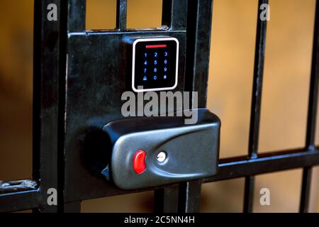 Le verrou de la grille en fer avec un trou pour la clé et un panneau tactile pour entrer la clé d'accès ou le mot de passe pour ouvrir l'entrée. Banque D'Images