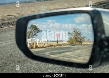 Vue sur un miroir de la vue arrière dans la Californie rurale, avec des boîtes aux lettres et un panneau d'arrêt dans le reflet Banque D'Images