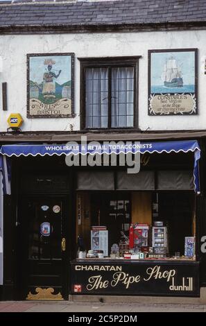 Deux publicités anciennes sur le tabac, peintes à la main sur des panneaux en bois, sont accrochées au-dessus de la vitrine d'un magasin de tabac : « The Shipp », faisant la promotion du tabac de Virginie de l'agent (à droite), et « The Black Boy », faisant la promotion des marchands de tabac, Wills & Co - racistes et profondément offensifs aux yeux modernes. Photographié en août 1999 sur la façade du tabac Marshall, également connu sous le nom de Pipe Shop, au 6 St. Mary’s Street, Ely, Cambridgeshire, Angleterre. Marshall a fermé en 2006 et ces panneaux vintage ont depuis longtemps disparu. Banque D'Images