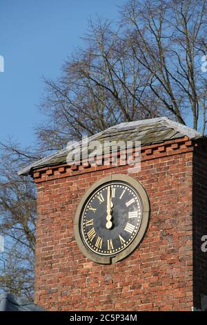 Une grande horloge extérieure sur une tour de bâtiment en brique. Banque D'Images