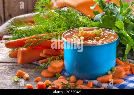 Soupe de carottes à la crème dans un bol bleu sur une table rustique en bois. Le concept de saine alimentation et de nutrition. Composition de style vintage. Banque D'Images